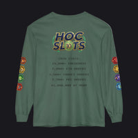 A sage green long-sleeve t-shirt with a humorous 'HOC SLOTS 10' graphic on the back, featuring gaming-themed text and colorful hexagonal icons down both sleeves.