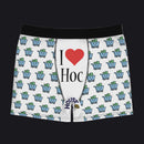 White boxer briefs with a black waistband, featuring a repeating pattern of blue shopping carts with green cash and a central graphic that reads 'I ♥ Hoc' with 'House of Cards' branding near the hem.
