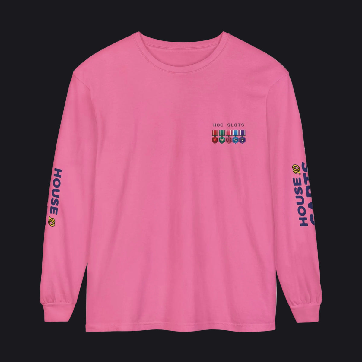 A pink long-sleeve crewneck t-shirt with a small multicolor graphic on the left chest and 'HOUSE OF CARDS' printed vertically in blue on both sleeves, shown against a plain white background.