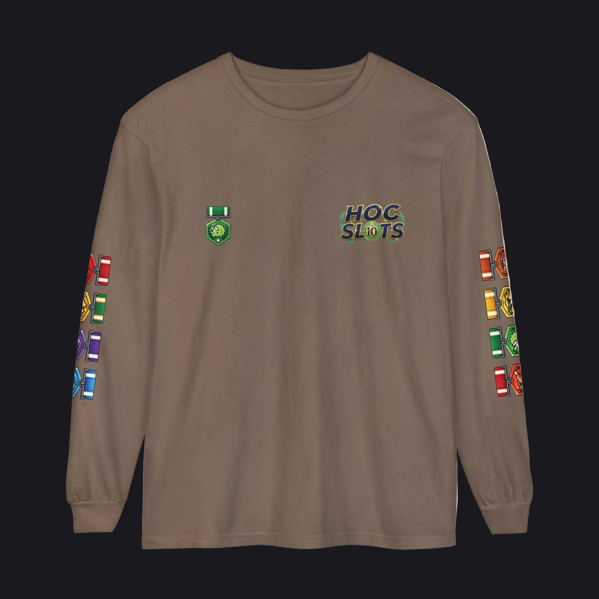 A brown long-sleeve t-shirt with 'HOC SLOTS' printed on the left chest, a green emblem on the right chest, and colorful game-piece graphics printed down both sleeves.