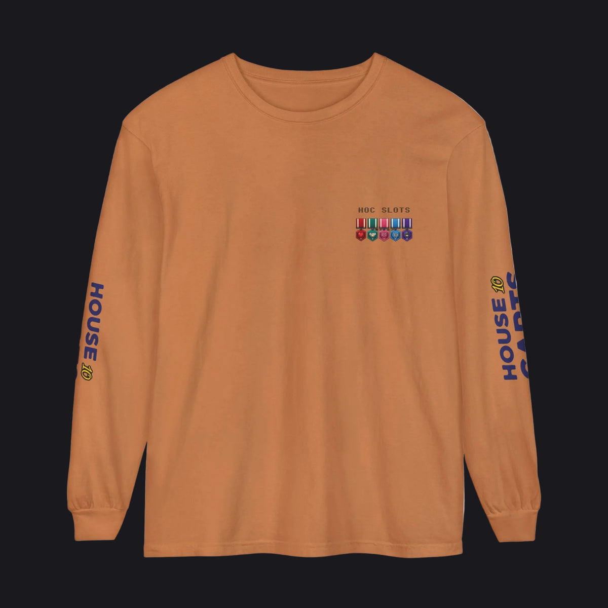 A long-sleeve crewneck t-shirt in a warm burnt orange color, featuring a small multicolor military ribbon graphic and 'MAY 21 RTO' printed on the left chest, with 'HOUSE CARDS' printed vertically in blue on both sleeves.