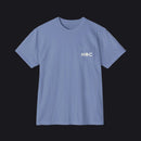 A light blue crewneck pocket t-shirt with a small white graphic on the left chest pocket, displayed flat against a white background.